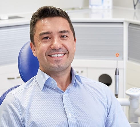 Man in dental chair smiling after oral cancer screening