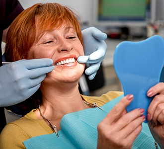 patient smiling while looking in dental mirror 