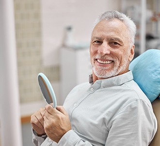 patient smiling while sitting in dental chair 