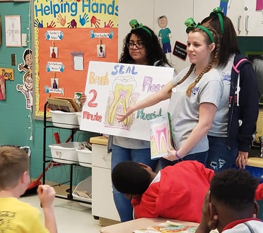 Dental team members showing kids a poster depicting the inside of a tooth