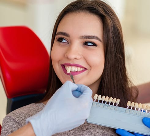 Woman's smile compared with porcelain veneer shade chart