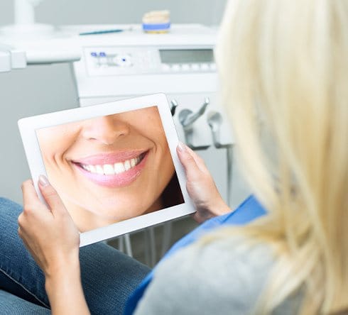 Woman looking at virtual smile design on computer screen