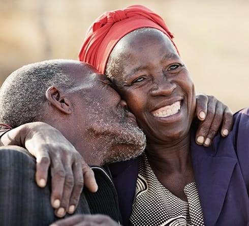 Man kissing woman with fixed dentures on her cheek