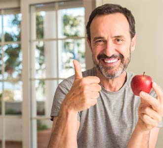 Man holding red apple while giving thumbs up