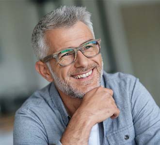 Man with grey hair smiling while wearing glasses