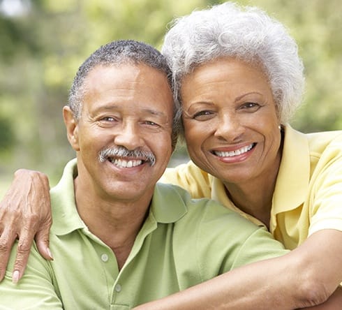 Man and woman smiling after replacing missing teeth with dental implants