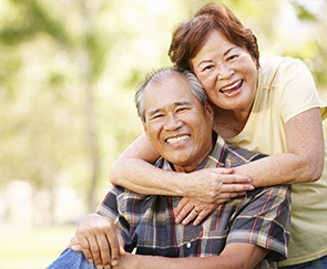 Man and woman smiling after replacing missing teeth