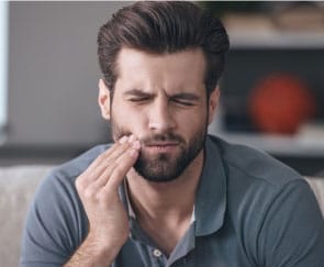 Man in need of emergency dentistry holding jaw