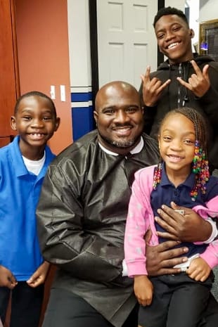 Doctor Marable posing with three young patients