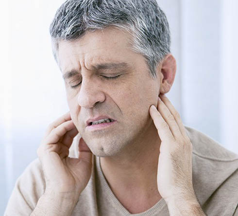 Man  in need of T M J therapy holding jaw in pain