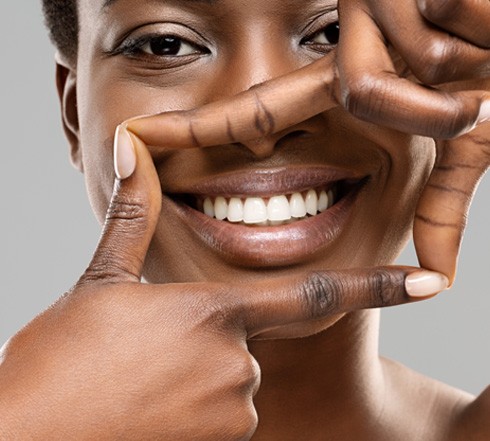 Woman framing her bright smile with both thumbs and pointers