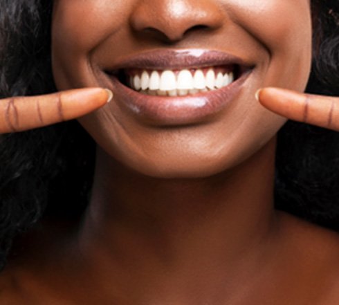 Woman pointing to her bright white smile