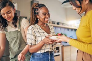Woman handing her friend a bowl of fruit